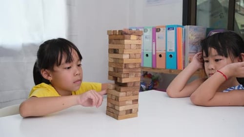Cute Asian siblings having fun playing Jenga together.