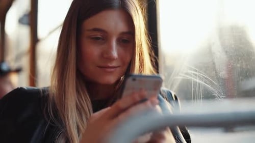 Uma mulher está interagindo com seu smartphone enquanto está sentada em um café aconchegante, aproveitando seu tempo