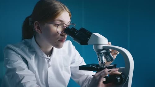 Young Adult Works with Microscope in a Lab