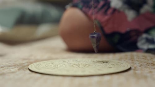 Amethyst Pendulum Dowsing Over Esoteric Chart on Table