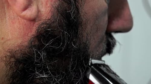 Man Trimming Black and Gray Beard with Razor