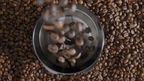 Coffee beans pouring into a grinder, birds eye