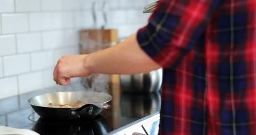 Man Cooking Food in Frying Pan Indoors