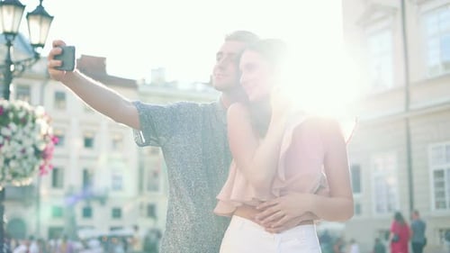 Young Couple in Love Standing on Street and Taking Pictures Selfie Photos People Using Smartphone to