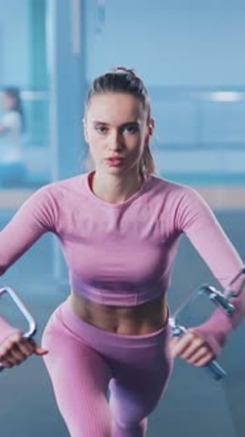Zoom-Porträt einer jungen und starken Fitnessfrau, die Sport treibt und im Fitnessstudio intensiv trainiert