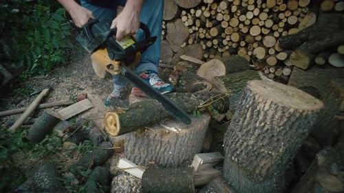 Slow Motion Closeup Video of a Man Cutting a Log with a Chainsaw