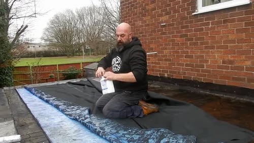 Man Spreads Liquid on Insulation with Roller