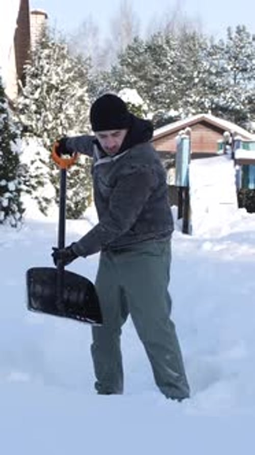 Man Shovels Snow in Residential Winter Setting