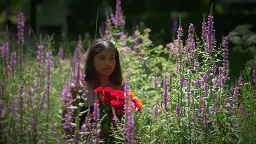 A Woman Stands Gracefully in a Vast Flower Field Holding Beautiful Bouquets of Flowers