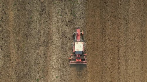 Top View Of Tractor Harrowing Soil In Agricultural Field