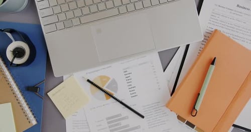 Top View Closeup of Office Desk with Laptop Computer and Business Documents on Desktop