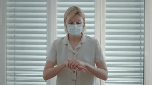 Woman Disinfecting Hands with Sanitizer Wearing Medical Mask