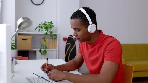 Young Man Attends Online Meeting and Takes Notes