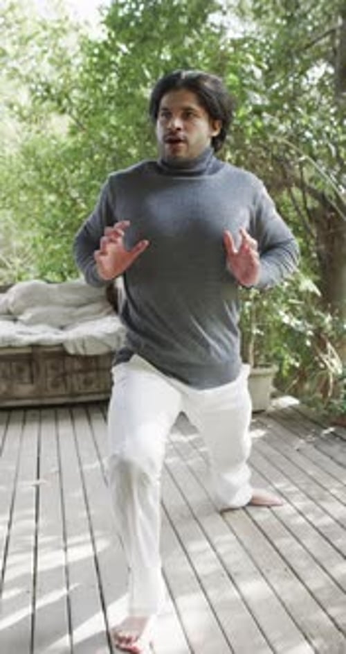 Vertical video of biracial man practicing yoga on terrace in nature, slow motion