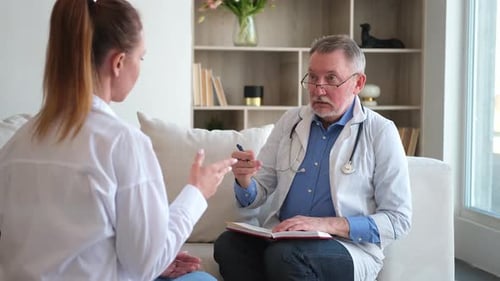 Senior Man Doctor Examining Yound Woman in Doctor Office or at Home Girl Patient and Doctor Have