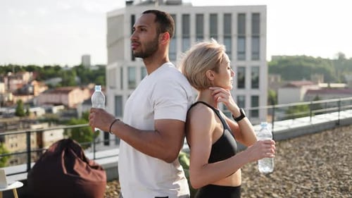 Fit Couple Drinking Water on City Rooftop