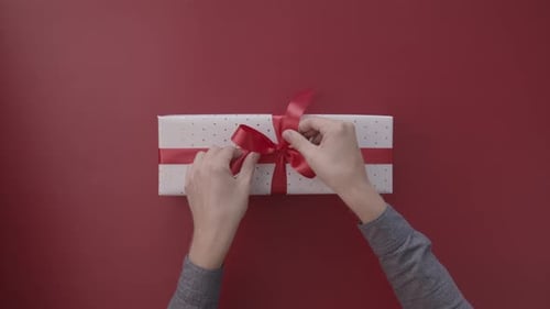 Gift Unwrapping with Red Ribbon on Red Surface