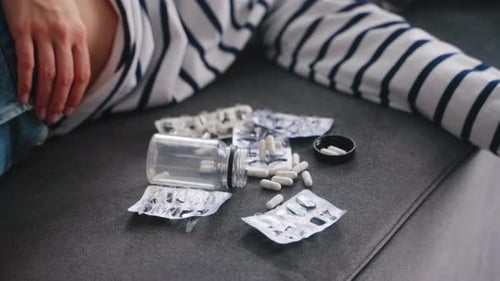 Une femme s'est suicidée par surdose de drogue est allongée sur le canapé à la maison près de plaquettes thermoformées vides et