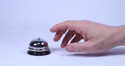 Hand moves into frame and the index finger taps concierge bell three times impatiently