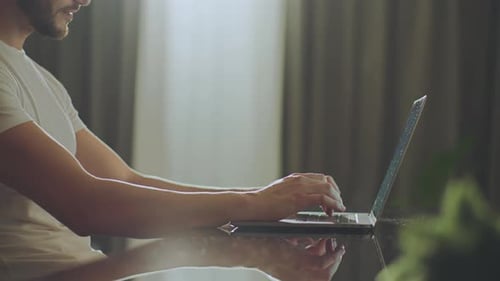 Man Typing on Laptop Computer at Home Desk