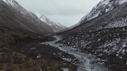 Aerial View of Winding River Through Mountainous Valley Camera Pans Smoothly