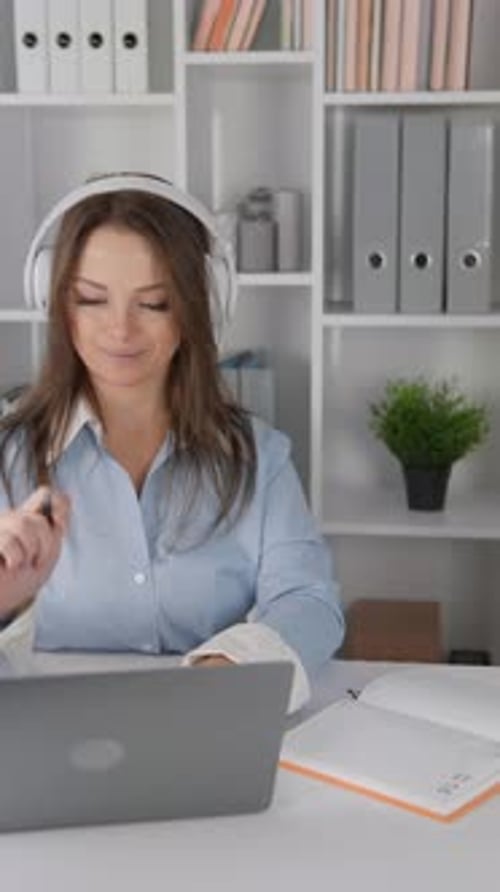 The Businesswoman in the Office is Focused on Her Laptop Wearing Headphones Reflecting Her
