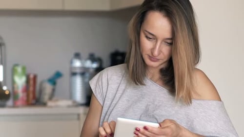 Woman using tablet device in kitchen