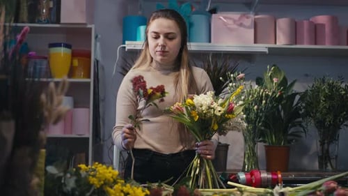 Portrait à taille moyenne d'une fleuriste professionnelle faisant un bouquet à l'intérieur, vue de face, jeune