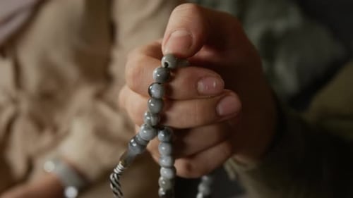 Muslimischer Mann hält Gebetsperlen während eines traditionellen Rituals zu Hause