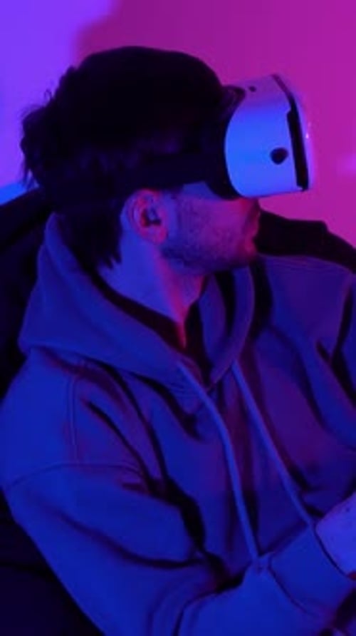 Männlicher Cybersport-Gamer mit Controller beim Spielen mit Virtual-Reality-Brille