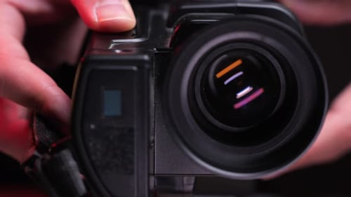 Hands Adjusting a Black Video Camera Lens