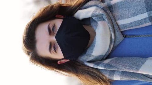 Young woman wearing black protective mask outdoors during coronavirus pandemic
