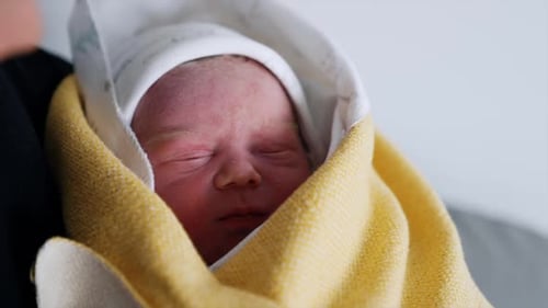 Peaceful Newborn Baby Wrapped in Yellow Blanket