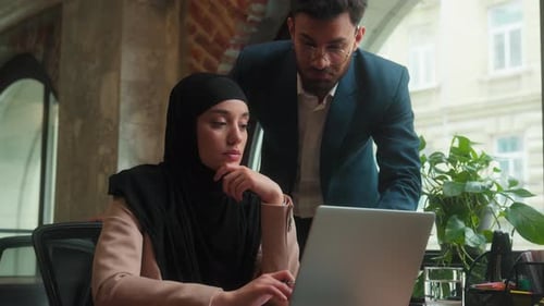 Male Businessman Teach Female Muslim Worker Hijab in Office Mentor Leader Help Laptop Work Consult