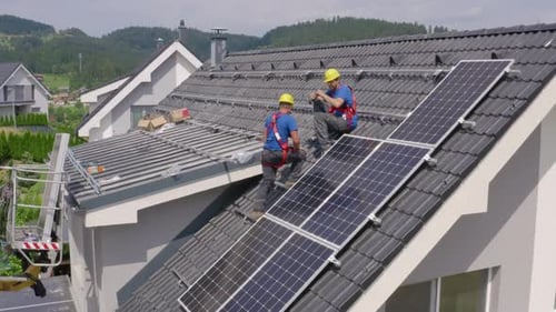 Workers Installing Solar Panels on a House Roof