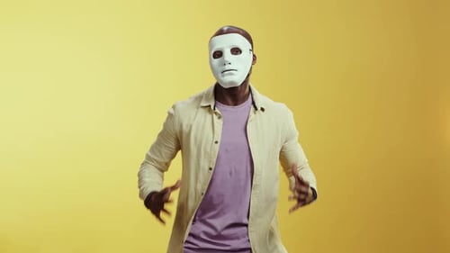 Ein maskierter Mann in einem lila Hemd tanzt faszinierend in Gelb