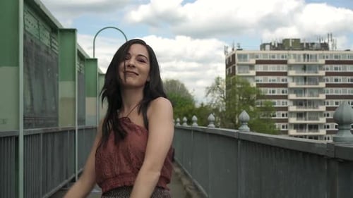 Happy and carefree Latina woman dancing on a bridge in London. Slow motion shot