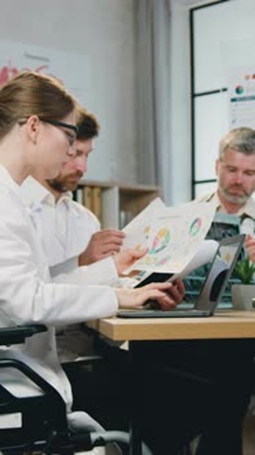 Medical Staff Reviewing Charts and Laptop in Office
