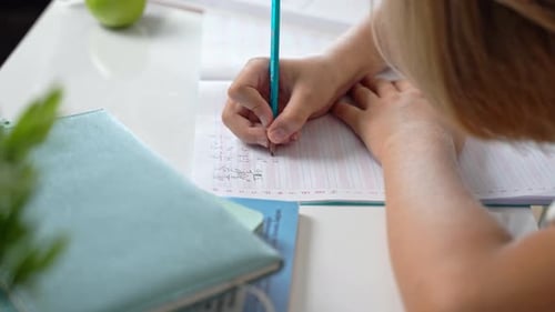 Middle School Smiling Student Boy Sitting at Desk Studying Writing Book Homework and Tablet at Class