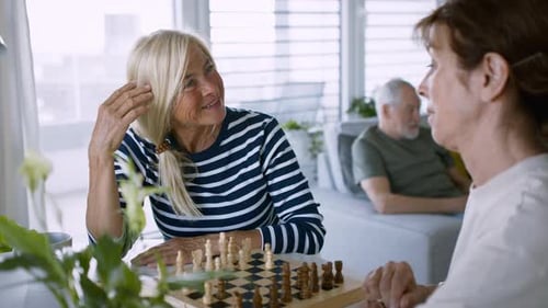 Two Senior Women Play Chess Indoors