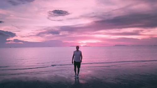 Caucasian Male Traveler Walks Along the Beach in the Evening Against the Backdrop of a Beautiful