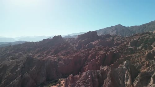 Aerial view drone flying over scenic rocky mountains with a clear blue sky.