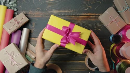 Gift Wrapper Man Hands Beautifully Gives It to Woman Top View Receiving Yellow Presents