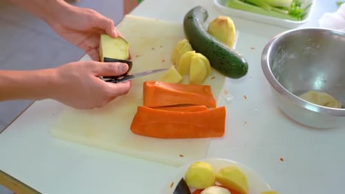 Close up of hands slicing fresh vegetables in kitchen. Static, high angle