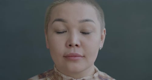 Zeitlupenporträt einer seriösen asiatischen Frau, die mit ruhigem Gesichtsausdruck in die Kamera schaut
