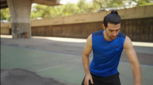 Un homme caucasien 4K s'entraîne au dribble sur un terrain extérieur.