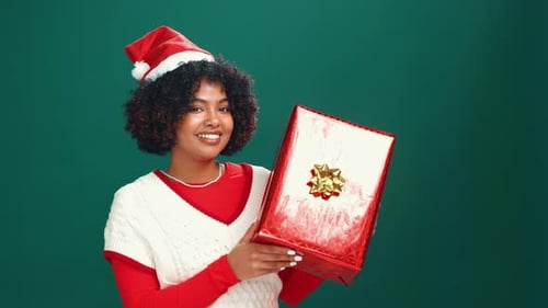 Happy, christmas gift and face of black woman in studio for celebration, giveaway or surprise