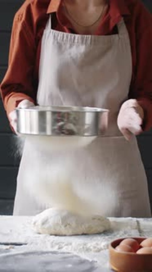 Baker Sifting Flour Over Ball of Dough