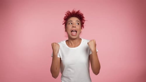 Joyful Curly Redhead African American Woman Rejoices in Victory Winning Gesture