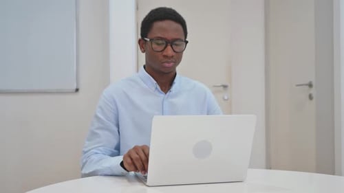 Young Adult Massaging Neck While Using Laptop